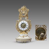 Pendule lyre en marbre blanc et bronze ciselé et doré, ornée d'un masque de femme rayonnant